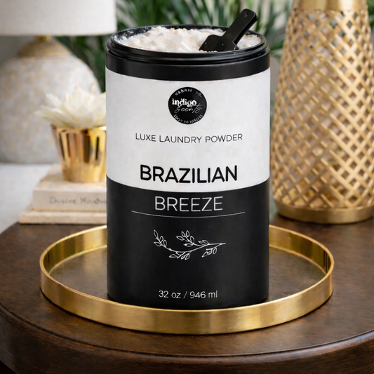 Luxe laundry powder container labeled 'Brazilian Breeze' on a gold tray with a home decor background.