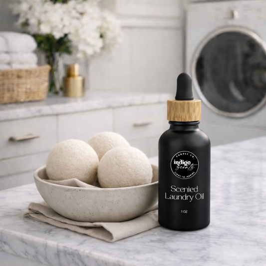 Luxury scented laundry oil by Indigo Scents displayed beside wool dryer balls on a marble countertop in a bright modern laundry room.