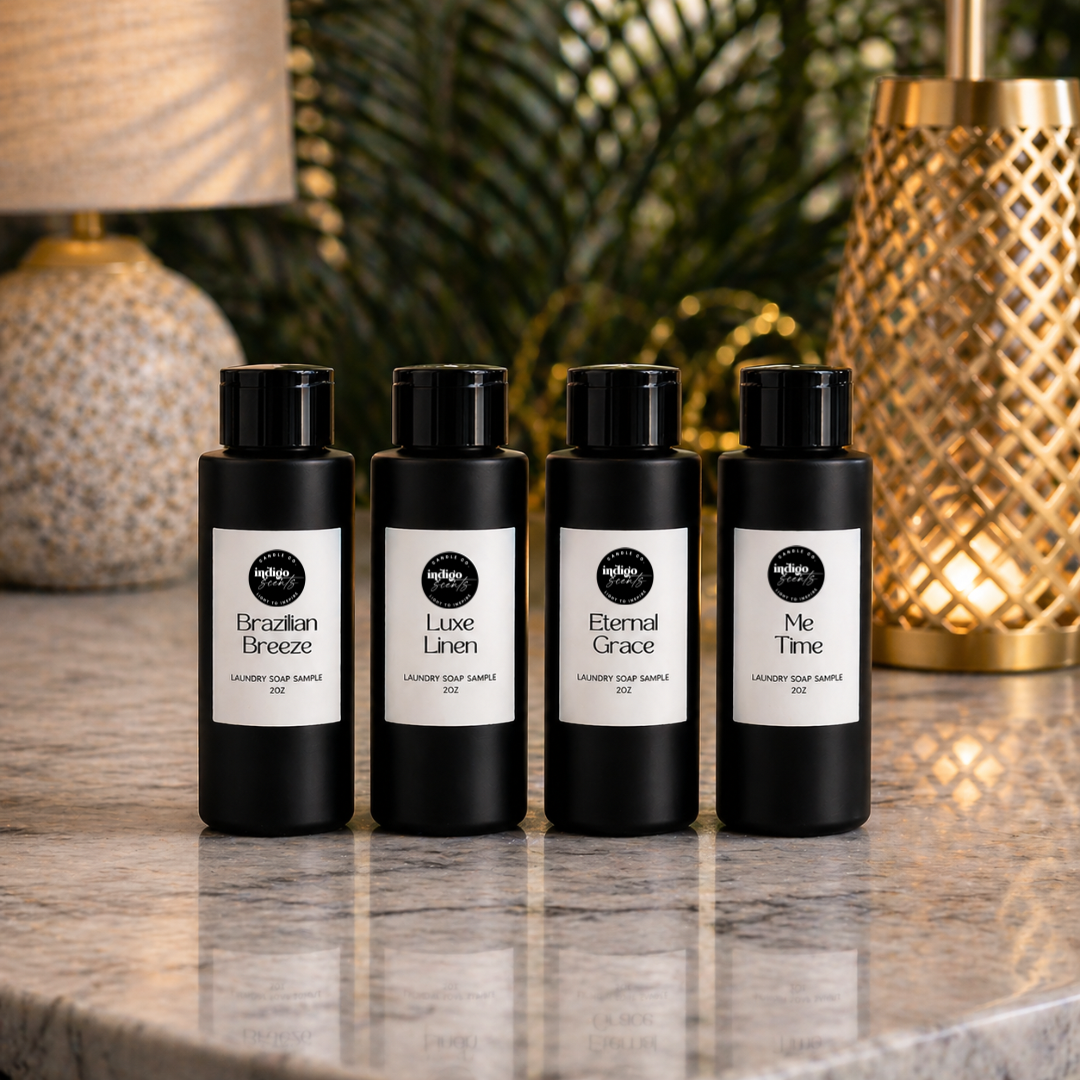 Four black bottles of liquid laundry wash with white labels on a marble surface with decorative lamps in the background.