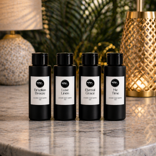 Four black bottles of liquid laundry wash with white labels on a marble surface with decorative lamps in the background.