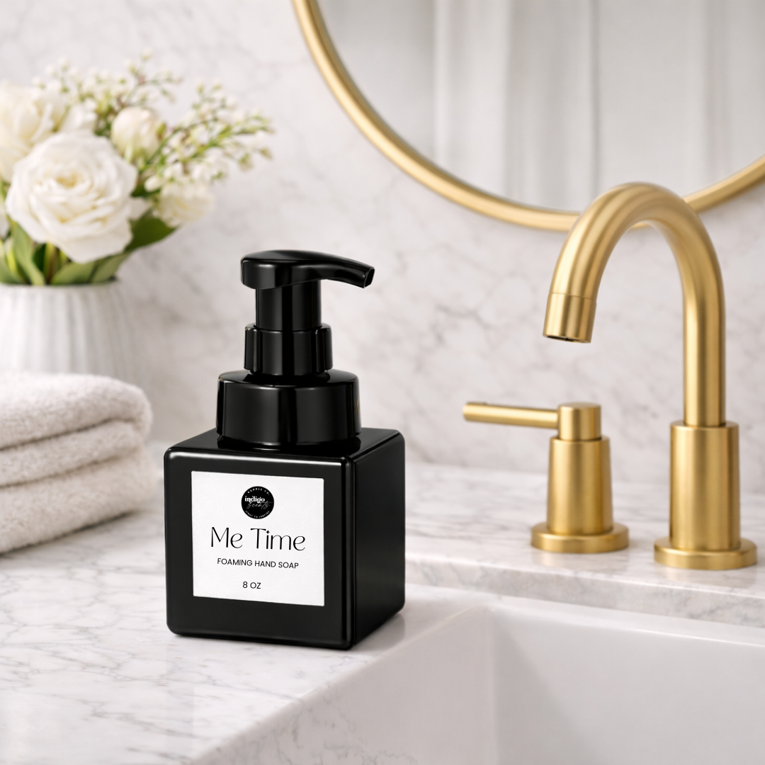 Indigo Scents Me Time foaming hand soap bottle on a marble bathroom sink with gold faucet and white flowers for a luxury bathroom aesthetic.